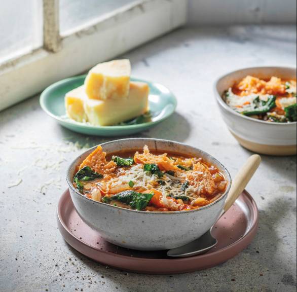 Gemüseeintopf in zwei Schalen auf einem Tisch, daneben eine Schüssel Parmesan und Brot