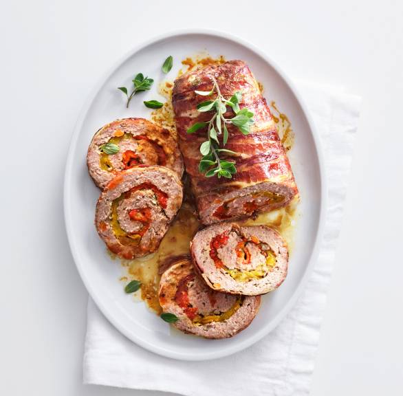 Hackbraten gerollt und angeschnitten auf einer Platte dekoriert mit Majoranzweigen