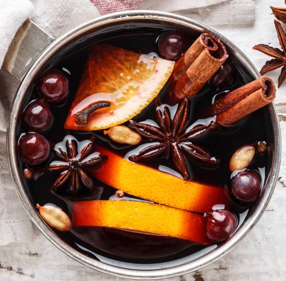 Selbst gemachter Glühwein in einem Topf, darin Blutorangenscheiben, Gewürze und Cranberries