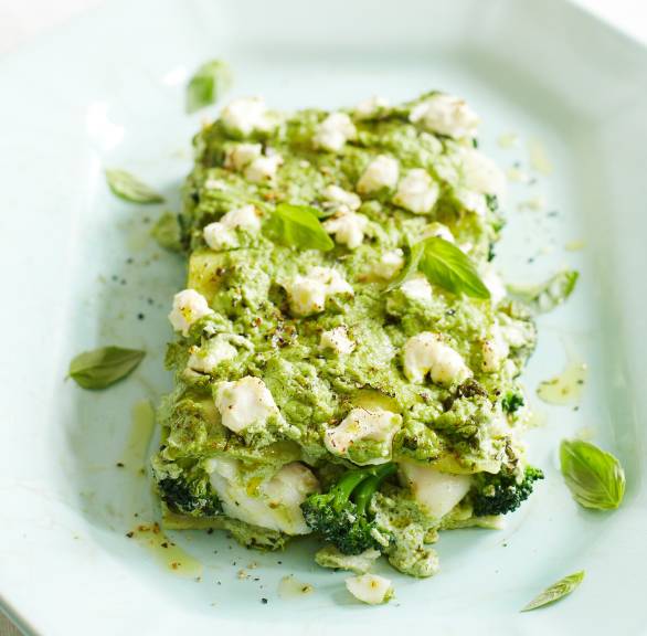 Ein Stück grüne Lasagne mit Brokkoli und Kabeljau getoppt von Käse und Basilikum auf einem Teller
