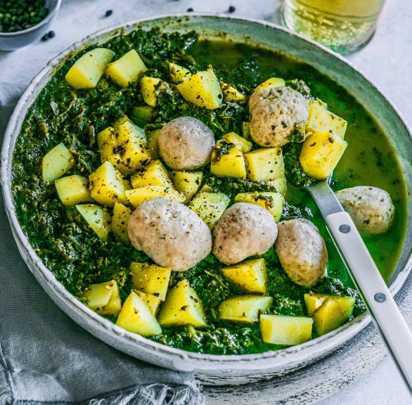 Italienischer Grünkohleintopf mit Kartoffeln und Speck getoppt von Salsiccia-Bällchen auf einem tiefen Teller