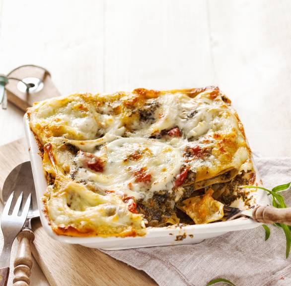 vegetarische Grünkohllasagne angeschnitten in einer viereckigen Auflaufform auf einem Tisch