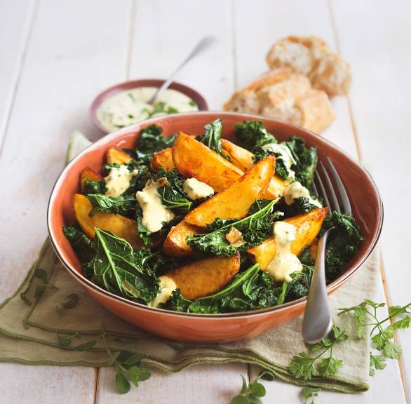 Grünkohlsalat getoppt mit Kartoffelspalten und Joghurt-Senf-Dressing in einem tiefen Teller