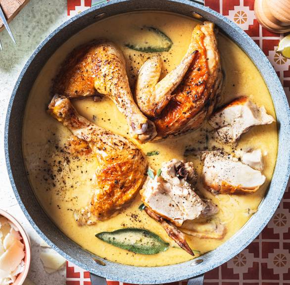 Hähnchenteile in einem Schmortopf mit Käse-Sahne-Soße und Salbeiblättern