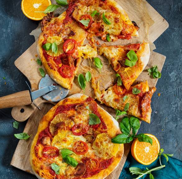 Zwei runde Pizzen mit Hähnchen-Orangen-Belag und Mozzarella auf Holzbrettern von oben