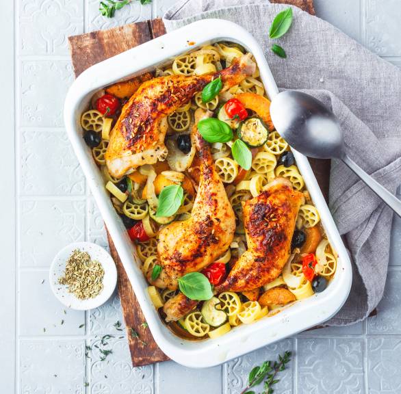 Gebackene Hähnchenkeulen auf Gemüsemix und Pfirsichen mit Rotelle-Nudeln in einer Auflaufform