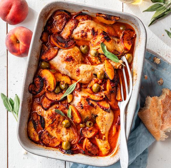 Gebackene Hähnchenschenkel mit Pfirsichen, Soße und Oliven in einer Auflaufform