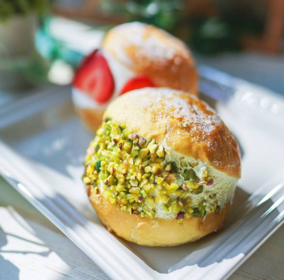 Zwei selbstgebackene Maritozzi Hefebrötchen gefüllt mit Sahne,  eines getoppt von Erdbeeren, eines mit Pistazien