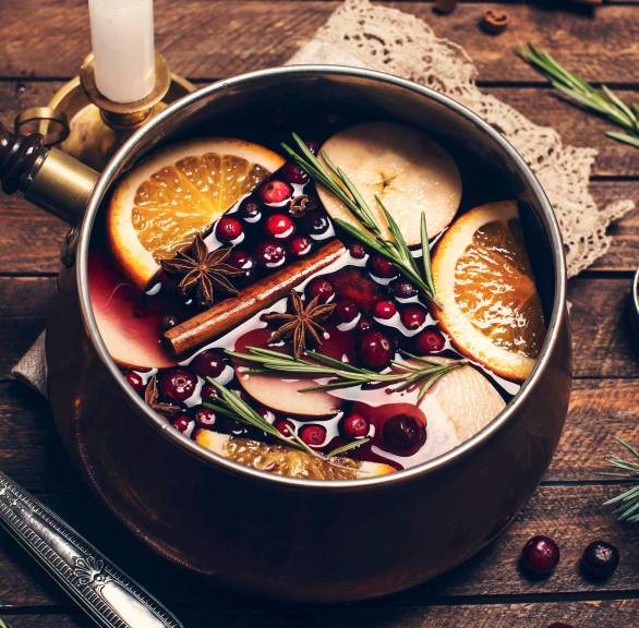 Selbst gemachter Früchtepunsch in einem Topf auf einem Holztisch mit Kerzen