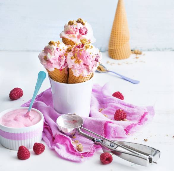Himbeereis mit Quark und Keksteig in Hörnchen gefüllt und in eine Tasse gestellt auf einem Tisch