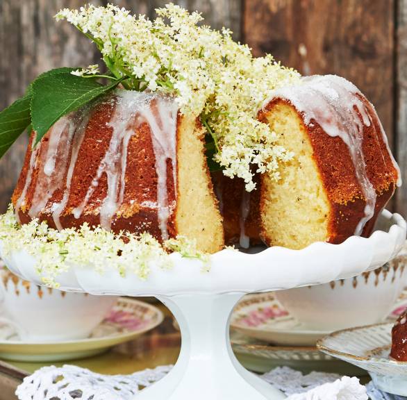 Gugelhupf mit Joghurt, Holunderblütensirup und Zitrone angeschnitten auf einer Tortenplatte