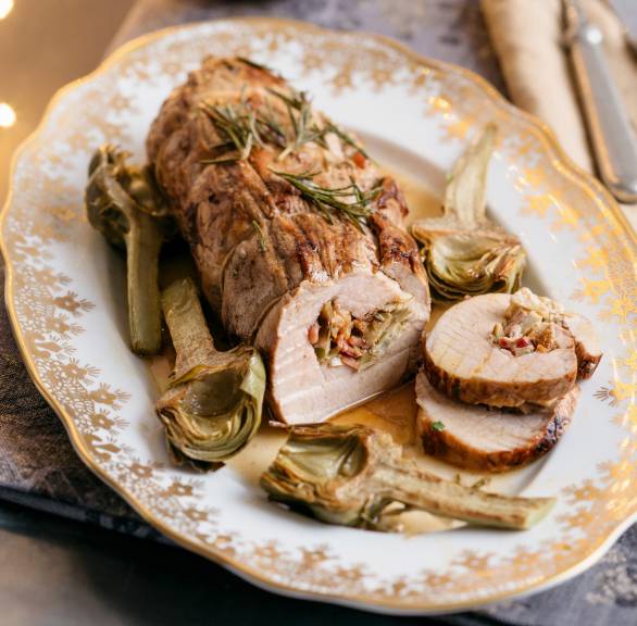 Italienischer Kalbsrollbraten mit Artischocken-Pfifferlings-Füllung und Walnüssen angeschnitten auf einer Servierplatte