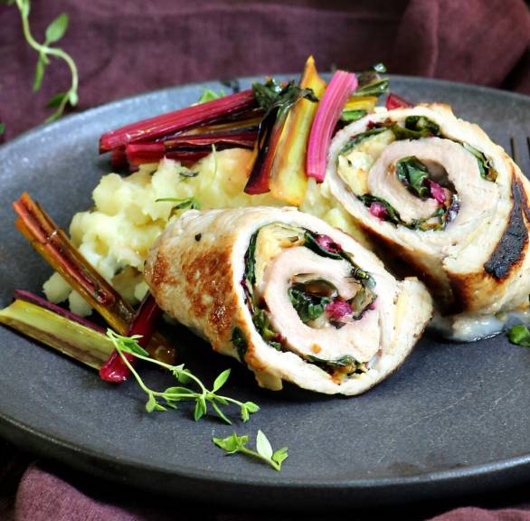 Zwei Schweine-Involtini mit Mangold-Taleggio-Füllung und Kartoffel-Pastinaken-Püree auf einem Teller