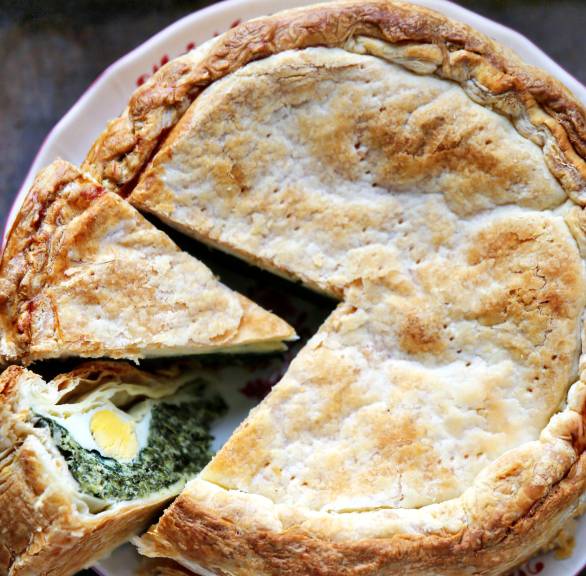 Runde italienische Ostertorte mit Spinat, Ricotta und Eiern angeschnitten auf einer Platte