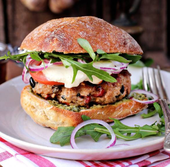 Italienischer Burger auf einem Teller, Patty, Mozzarella und Rucola erkennbar