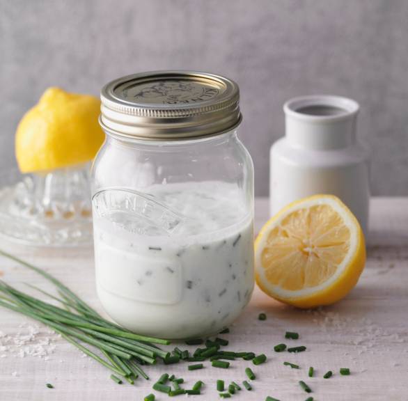 Joghurt-Dressing in einem Weckglas auf deinem Tisch, daneben Zitrone und Schnittlauch