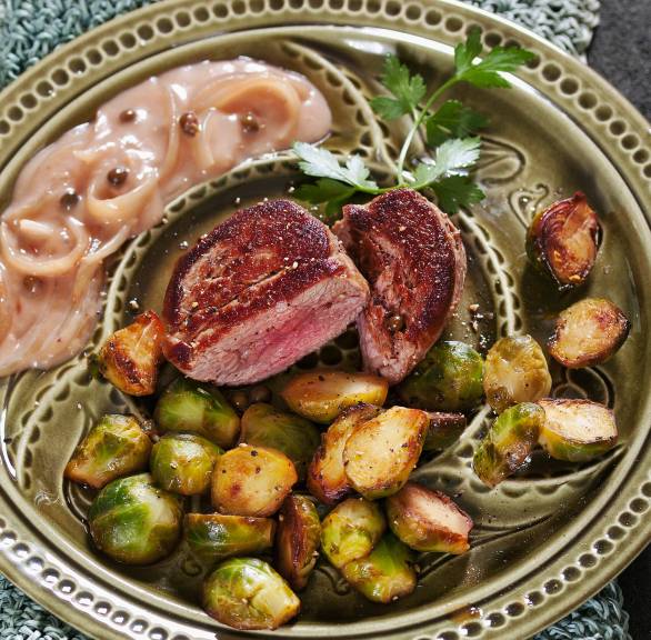 Kalbsmedaillons in der Mitte eines Tellers, drumherum gebratener Rosenkohl