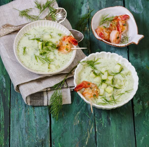 Gurkensuppe in mehreren Schüsseln getoppt mit gebratenen Garnelen und Dill auf einem Tisch
