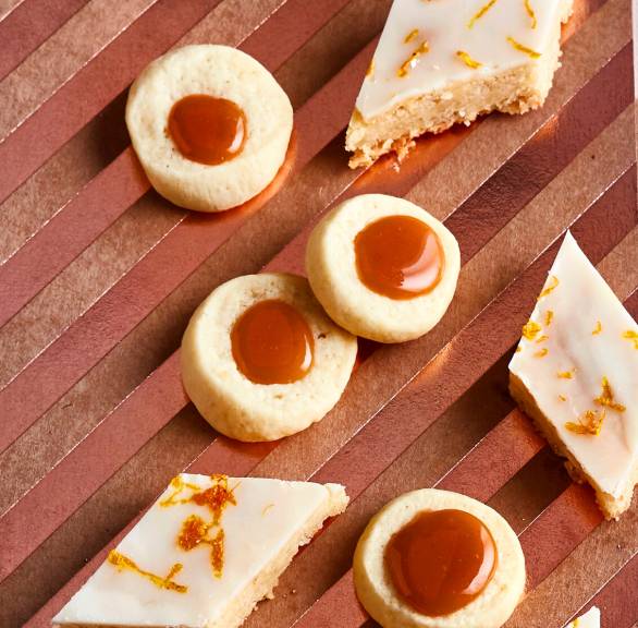 Runde Karamellkekse und rautenförmige Weihnachtsplätzchen auf einem Holzbrett