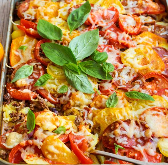 Kartoffelauflauf auf einem Backblech mit Tomaten, Hackfleisch und Käse überbacken