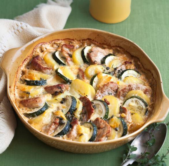 Zucchini-Kartoffelgratin mit Schweinefilet mit Käse überbacken in einer runden Auflaufform