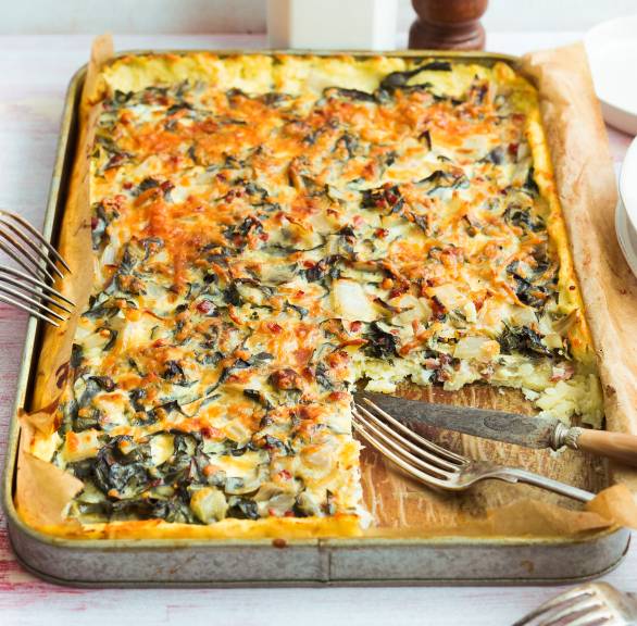 Glutenfreier Kartoffelkuchen mit Mangold und Speck angeschnitten auf einem Backblech