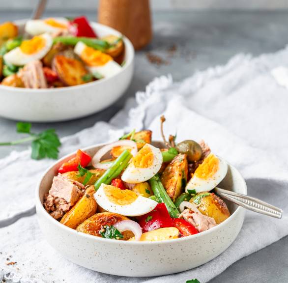 Italienischer Kartoffelsalat in zwei Salatschüsseln getoppt mit Eiern, grünen Bohnen und Thunfisch