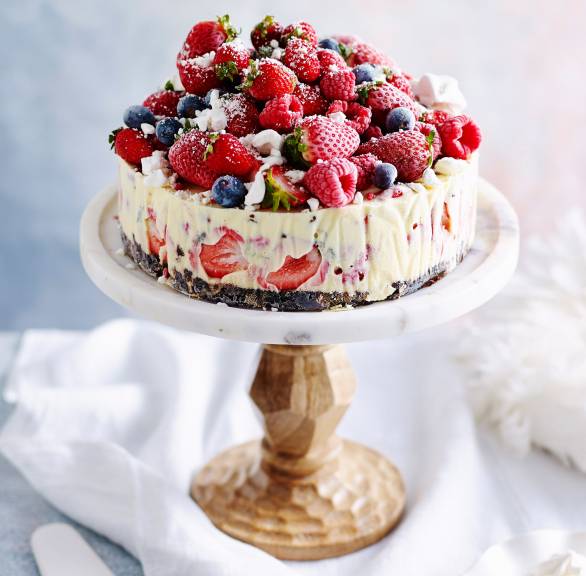 Eistorte mit Keksboden und Stracciatellaeis üppig mit frischen Beeren dekoriert auf einer Kuchenplatte