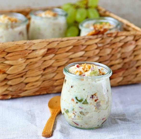Mehrere Gläser mit selbstgemachtem Frucht-Müsli mit Joghurt getoppt von Haselnusskrokant auf einem Frühstückstisch