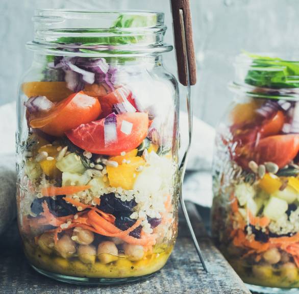 Bunter Quinoa-Salat mit Kichererbsen aus geschichteten Zutaten in einem Schraubglas