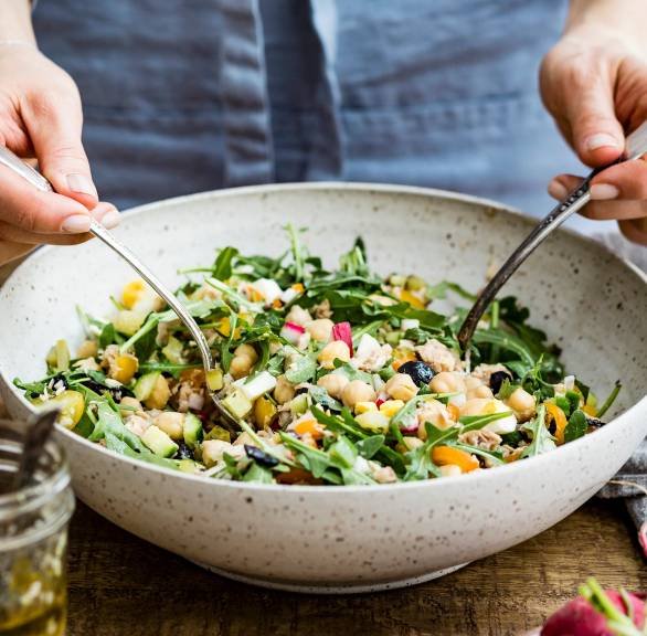 Bunter Thunfischsalat mir Kichererbsen wird gerade in einer Salatschüssel umgerührt