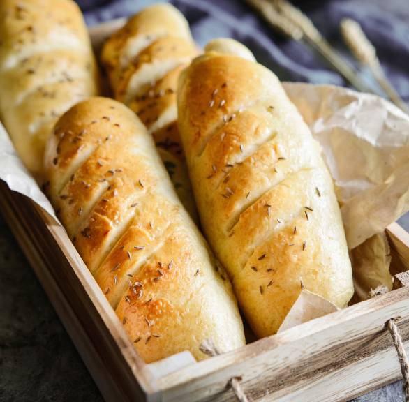 Vier selbstgebackene Seelen mit Knoblauch getoppt von mit Kümmelsaat in einer Holzkiste angerichtet