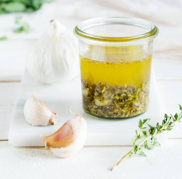 Selbstgemachte Knoblauch-Marinade in einem Weckglas auf einem Holztisch