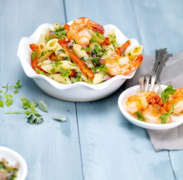 Nudelsalat getoppt mit Garnelen in einer Salatschüssel auf einem Tisch