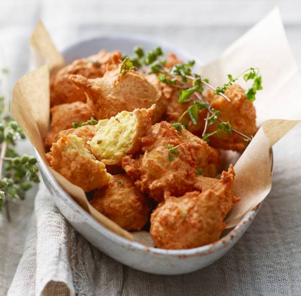 Frittierte Kichererbsenbällchen in einer Schale getoppt mit frischen Kräutern, daneben ein Dip
