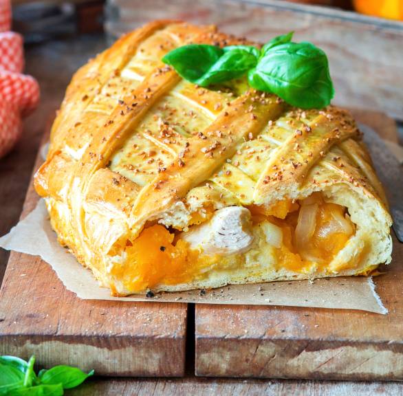 Kürbisstrudel mit Hähnchen gefüllt angeschnitten auf einem Holzbrett