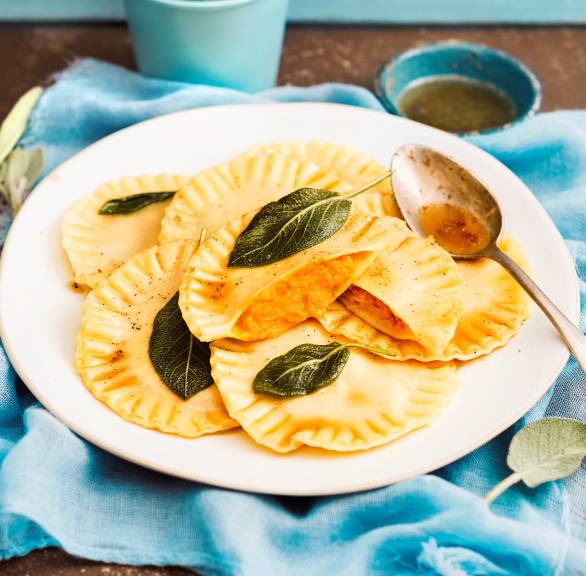 Ravioli auf einem Teller, einige halbiert, sodass die Kürbisfüllung sichtbar ist