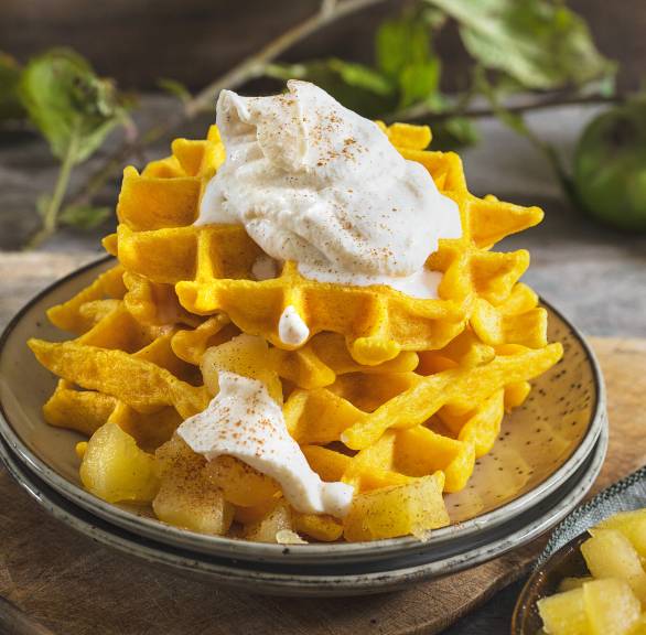Kürbiswaffeln gestapelt auf einem Dessertteller getoppt mit Zimtsahne