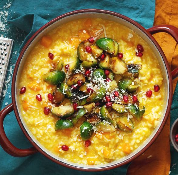 Safranrisotto in einem Topf getoppt mit karamellisiertem Rosenkohl, Parmesan und Granatapfelkernen