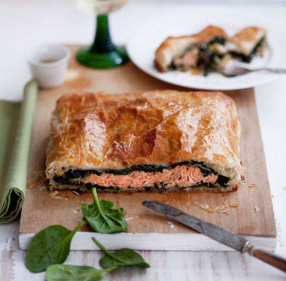 Lachs und Spinat im Blätterteigmantel angeschnitten auf einem Holzbrett