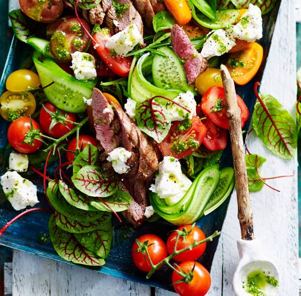Mangold-Salat mit Tomaten, Lamm, Feta und Pesto auf einem rechteckigen Teller