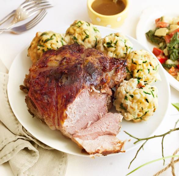 Angeschnittener Lammbraten mit Bärlauchknödeln auf einem Teller