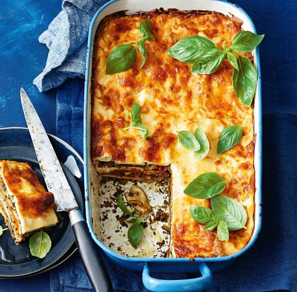 Lasagne mit Grillgemüse, Ricotta und grünem Pesto angeschnitten in einer Auflaufform von oben auf einem Tisch
