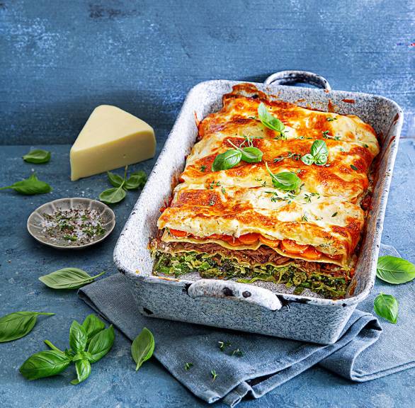 Wirsinglasagne mit Rinderbraten angeschnitten in einer Auflaufform, daneben Parmesan auf einem Tisch