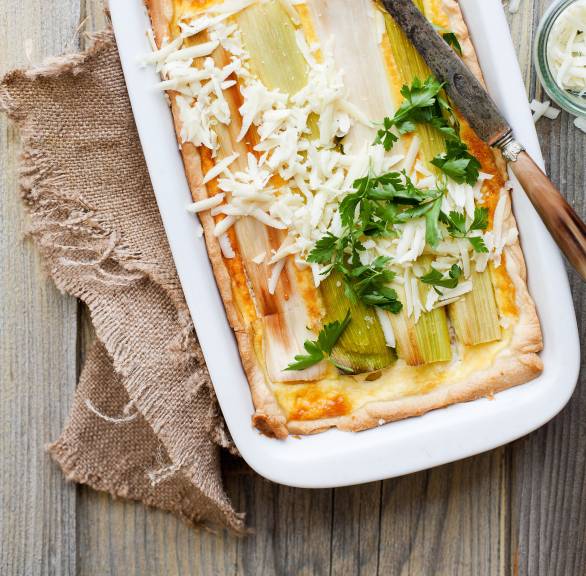 Blätterteig-Auflauf mit Schinken in einer Auflaufform belegt mit Lauchstangen und überbacken mit Käse