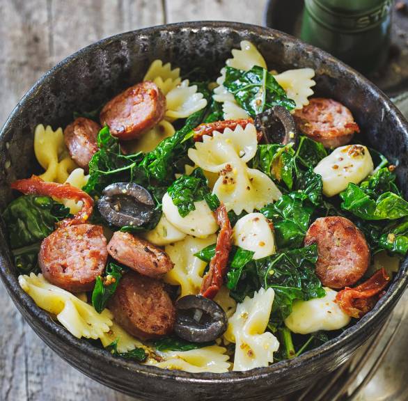Lauwarmer Grünkohl-Nudel-Salat in einer Schale getoppt mit mit Salsiccia, Mozzarella und Oliven