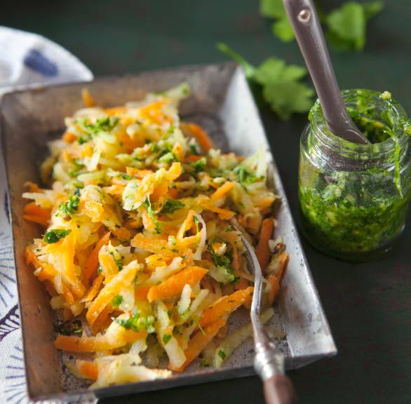Lauwarmer Karotten-Kohlrabisalat angerichtet auf einem Teller, daneben Petersilienpesto in einem Glas