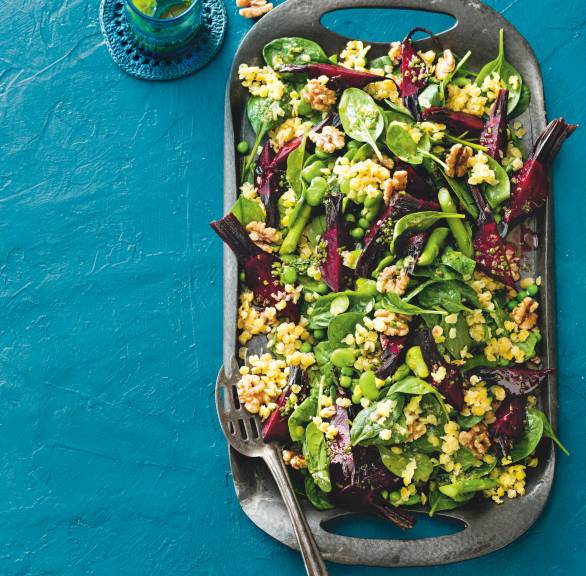 Veganer Linsensalat mit Rote Bete, Bohnen und Spinat auf einer Servierplatte getoppt von Walnüssen, daneben Ingwerdressing