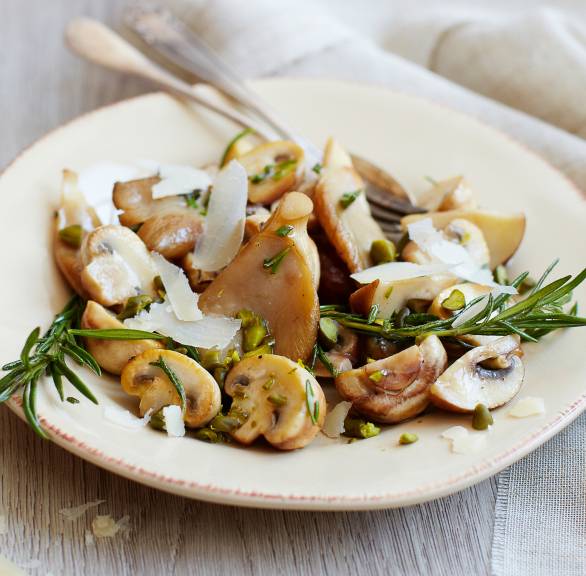 Marinierter Pilzsalat mit Pistazien und Parmesan getoppt von Rosmarinzweigen auf einem Vorspeisenteller