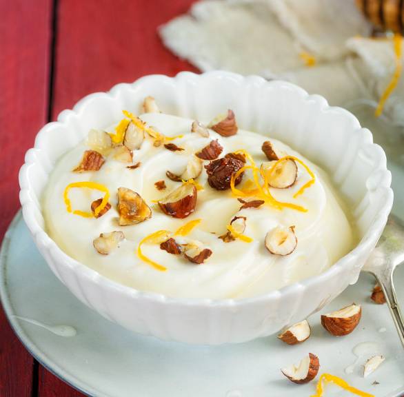 Mascarpone-Nachtisch in Glasschalen garniert mit Honig, Haselnüssen und Orangeszesten
